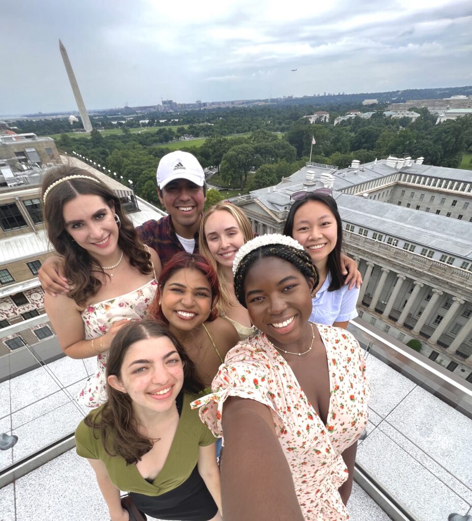 Daniella with other UC students, smiling from a high place overlooking buildings and the Washington Monument in the background.