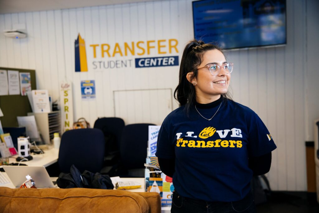A Transfer Center worker smiling in front of their work desk.