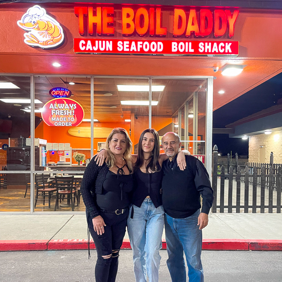 Jennifer poses with two family members in front of their restaurant, The Boil Daddy.