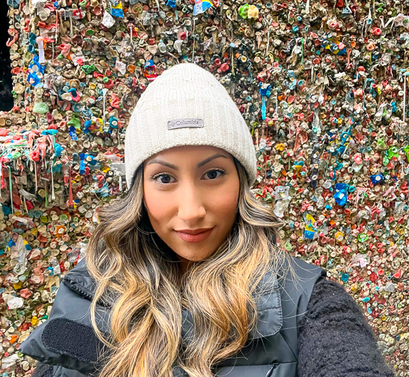 A selfie of Celina in front of a gum wall.